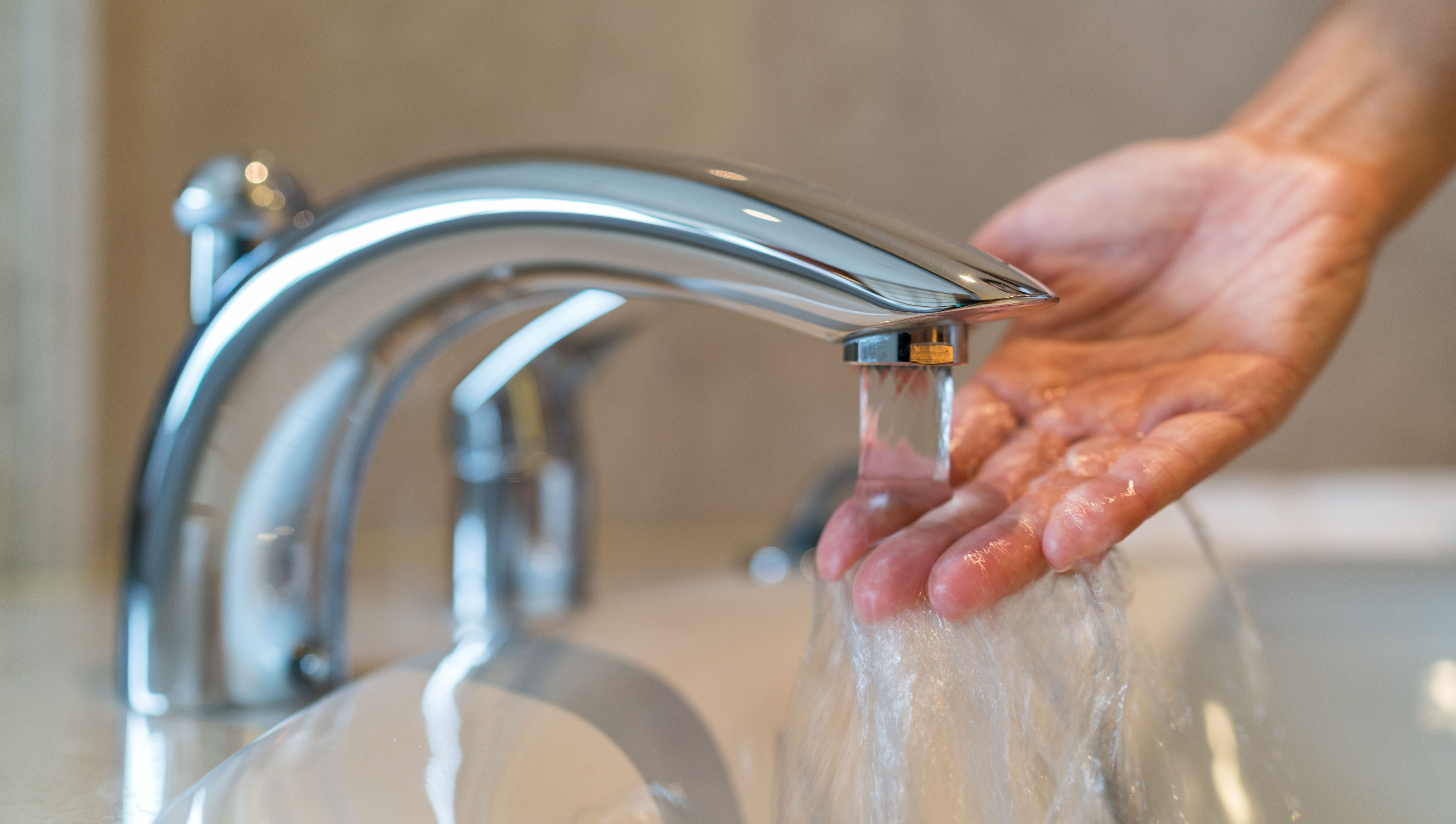 Hand washing in hot water from bathroom faucet