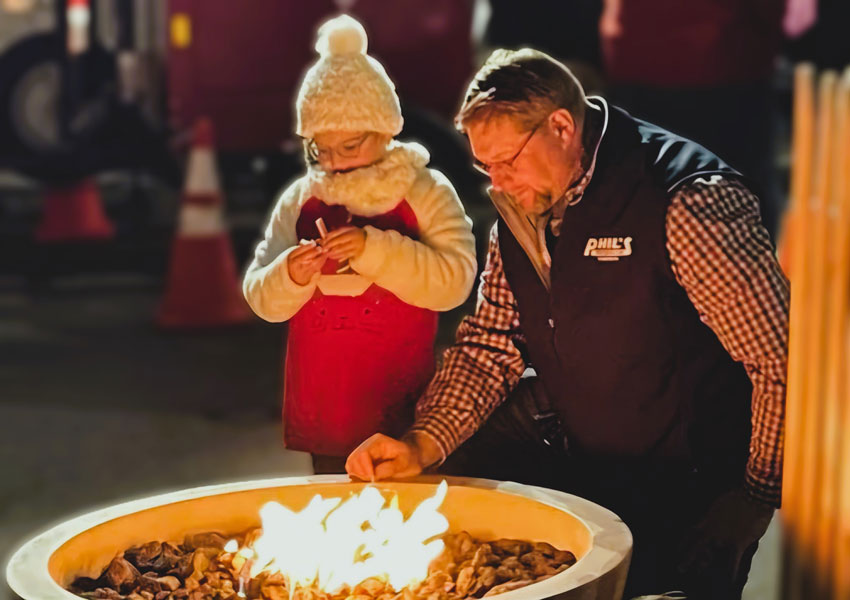 man with daughter standing around propane fire bowl to stay warm